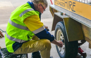 Busselton Equipment Hire mechanic inspecting a trailer wheel bearing and tyre at the BEH workshop