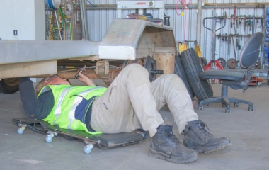 Mechanic lying on a creeper board and working underneath a trailer in a Busselton workshop