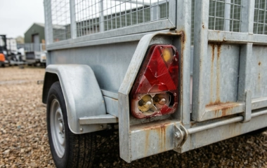 Cracked and damaged trailer tail light on a rusted galvanised cage trailer, showing why pre-trip light checks matter