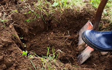 Hand-dug post hole with a shovel and boot, the manual work a hired digger avoids